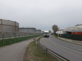 Asphaltierter Radweg, daneben eine Straße ohne Gehsteige, auf der Straße fährt gerade ein LKW