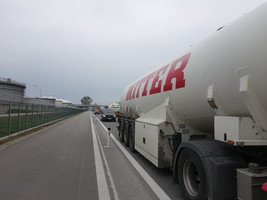 Asphaltierter Radweg, daneben eine Straße ohne Gehsteig mit dichtem LKW-Verkehr