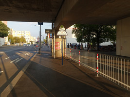 Bushaltestelle, mittig der Wartebereich, links die Fahrspur, rechts ein Abtrenn-Geländer, der den Wartebereich vom restlichen Gehsteig, über den dort ein Radweg verläuft trennt