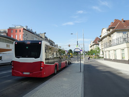 Von rechts nach links: Gehsteig, daneben Radweg, daneben eine Haltestellenwartefläche, daneben zwei KFZ-Fahrspuren in gleicher Richtung, eine davon auch als Abbiegespur, auf der ein 22A-Bus im Haltestellenbereich hinter der Ampel wartet, aber nicht die Türen öffnen darf